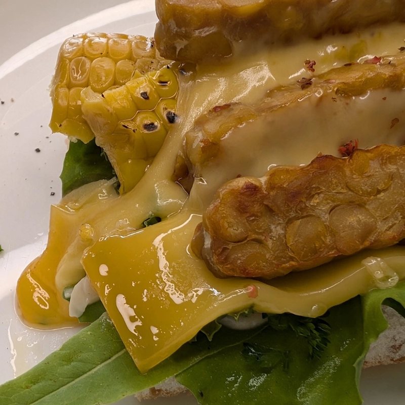 Kichererbsen-Tempeh-Sandwich mit Mais & geschmolzenem Käse
