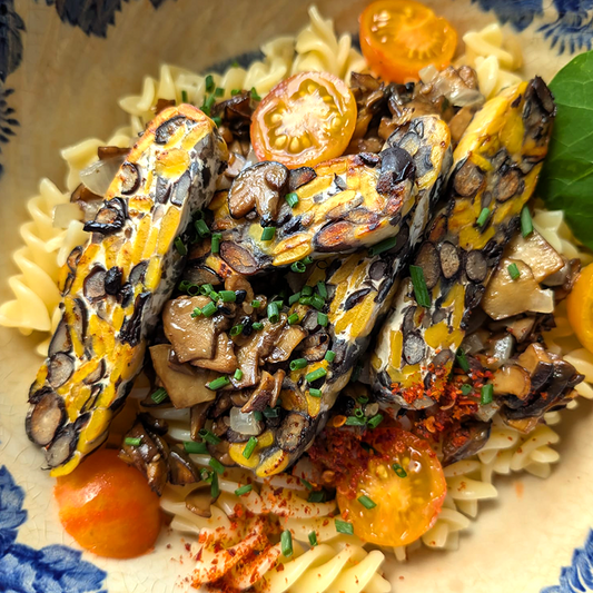 Nudeln mit Maronen, gelben Tomaten und gebratenem Dreiklang-Tempeh, bestreut mit Schnittlauch und Chiliflocken